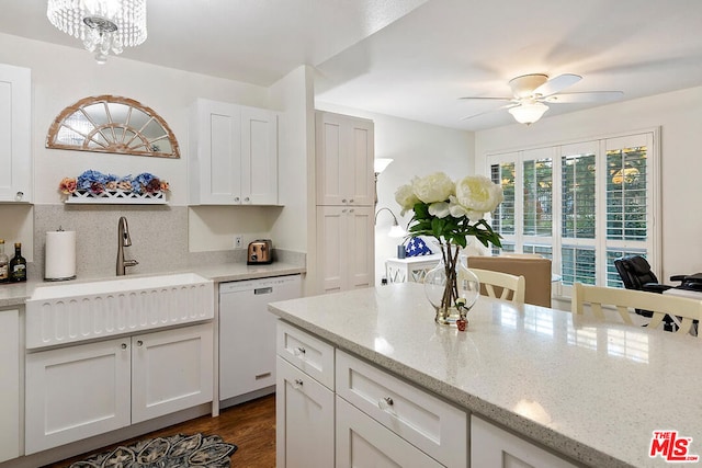 kitchen with light stone countertops, white cabinets, ceiling fan with notable chandelier, dishwasher, and dark hardwood / wood-style floors