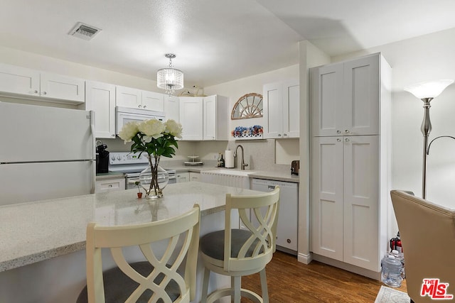 kitchen featuring light stone countertops, a breakfast bar, white appliances, decorative light fixtures, and white cabinets