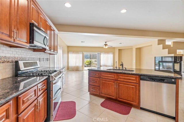 kitchen with ceiling fan, backsplash, dark stone countertops, sink, and appliances with stainless steel finishes