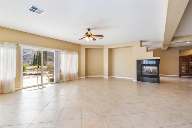 unfurnished living room with ceiling fan, beam ceiling, a tiled fireplace, and light tile patterned flooring