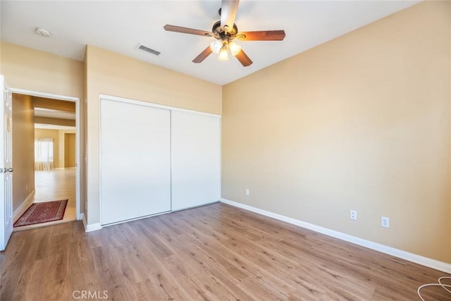 unfurnished bedroom featuring ceiling fan, light hardwood / wood-style floors, and a closet