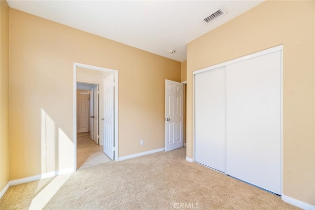 unfurnished bedroom with a closet and light carpet