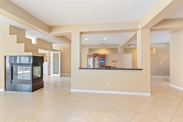 kitchen featuring kitchen peninsula, a tiled fireplace, and light tile patterned flooring