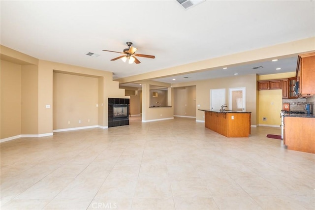 unfurnished living room featuring ceiling fan, sink, and a fireplace