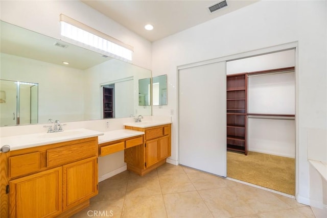 bathroom featuring a shower with shower door, vanity, and tile patterned flooring