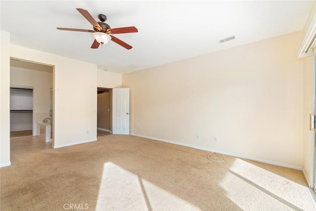 unfurnished bedroom with ceiling fan, light colored carpet, a closet, and a walk in closet