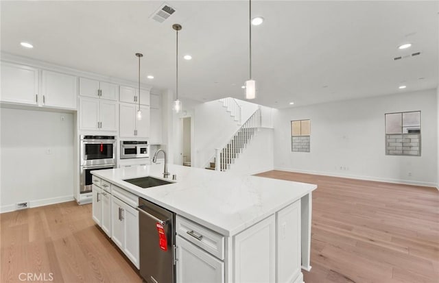 21235 Wildflower Way, Chatsworth, CA 91311 - kitchen featuring stainless steel appliances, white cabinets, light wood-type flooring, a center island with sink, and recessed lighting