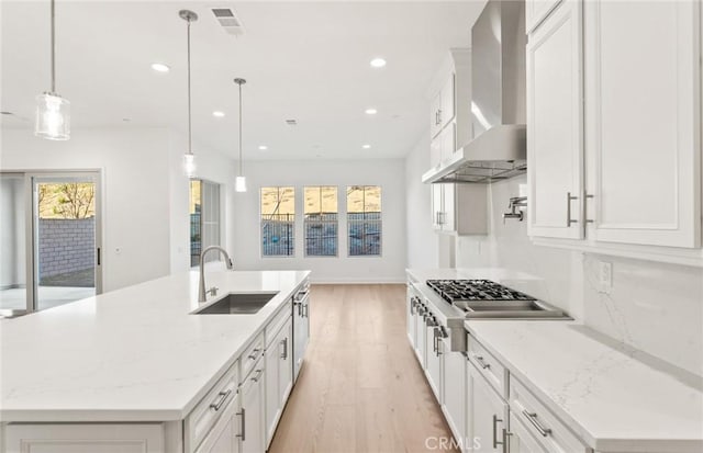 21235 Wildflower Way, Chatsworth, CA 91311 - kitchen with wall chimney exhaust hood, light wood-style floors, white cabinetry, recessed lighting, and an island with sink