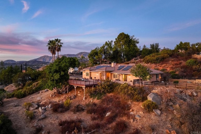 back house at dusk featuring a mountain view and solar panels