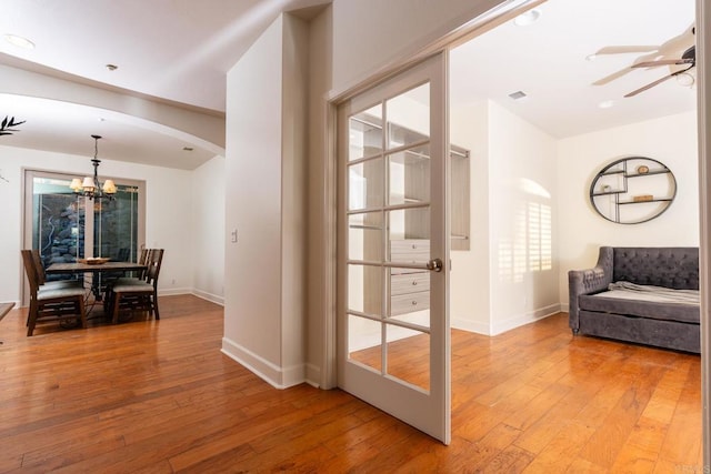 interior space with wood-type flooring and ceiling fan with notable chandelier