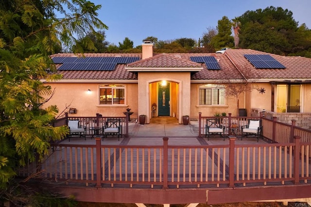 back house at dusk with a patio area, outdoor lounge area, and solar panels