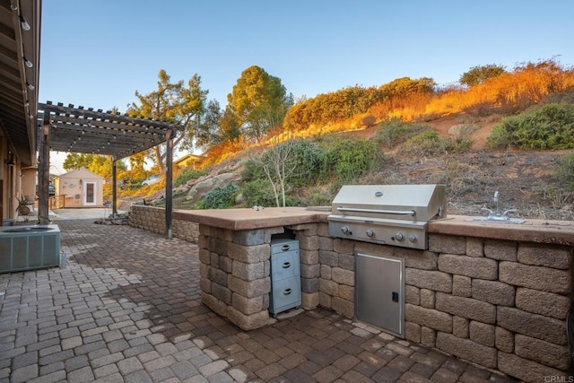 view of patio featuring exterior kitchen, a pergola, grilling area, and central AC