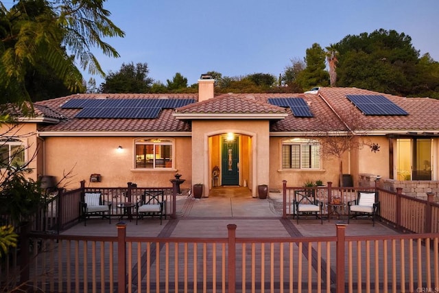 back house at dusk with an outdoor living space, a patio, and solar panels