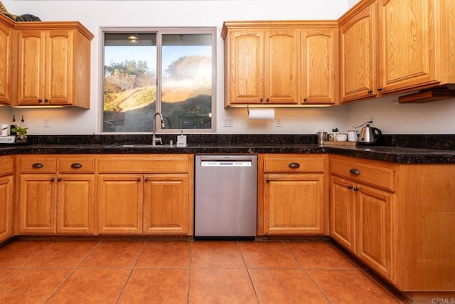 kitchen with sink, stainless steel dishwasher, light tile patterned floors, and dark stone countertops