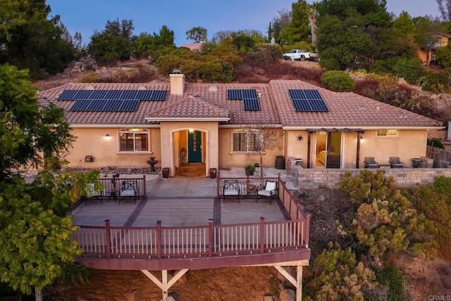 rear view of property with a deck and solar panels