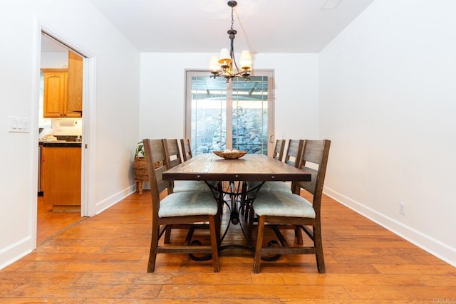 dining area with light hardwood / wood-style flooring and an inviting chandelier