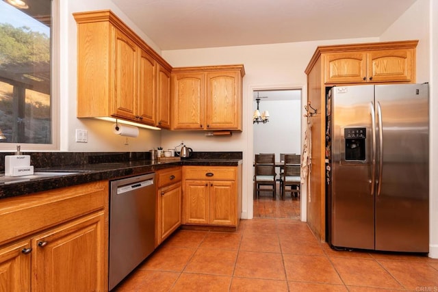 kitchen featuring light tile patterned flooring, dark stone countertops, and stainless steel appliances