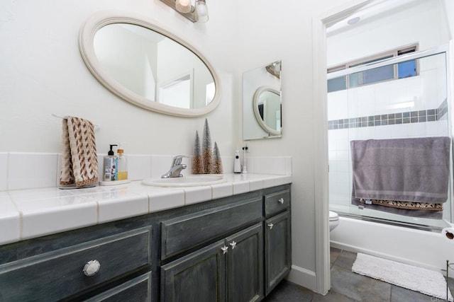 full bathroom featuring vanity, shower / bath combination with glass door, and toilet