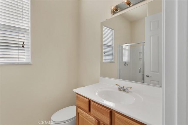 bathroom featuring vanity, toilet, and a shower with shower door