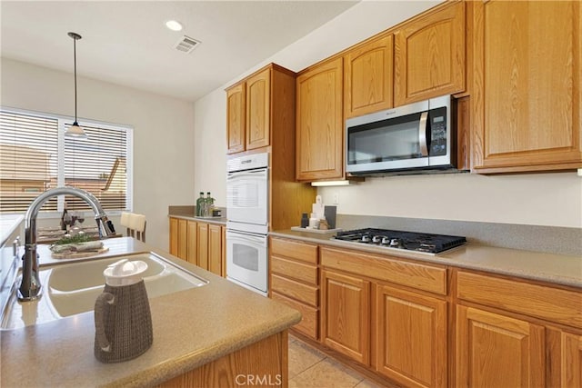 kitchen featuring pendant lighting, sink, light tile patterned floors, and stainless steel appliances