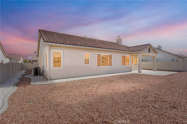 back house at dusk with a patio and central AC unit