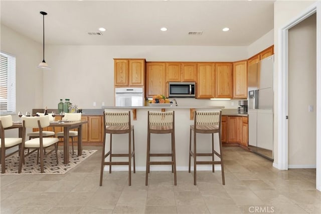 kitchen with pendant lighting, a center island, and white appliances