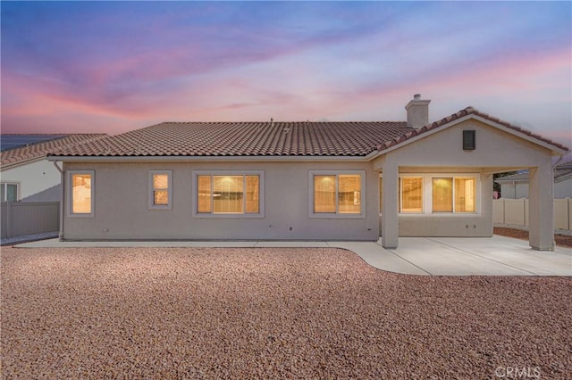 back house at dusk featuring a patio