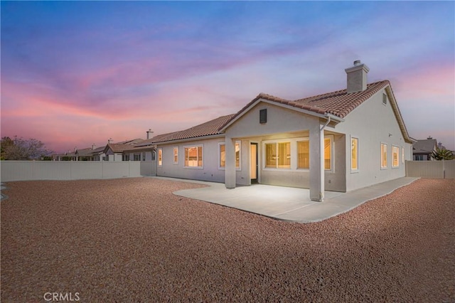 back house at dusk featuring a patio area