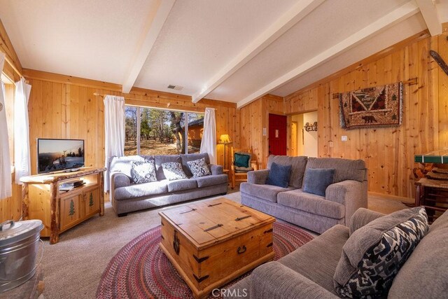 carpeted living room with wood walls and lofted ceiling with beams