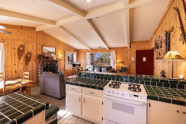 kitchen with tile countertops, wood walls, white stove, and vaulted ceiling with beams