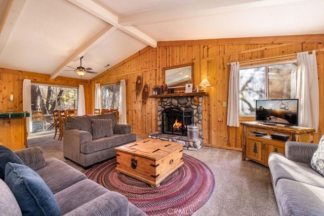 carpeted living room with vaulted ceiling with beams, ceiling fan, a fireplace, and wooden walls