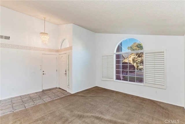 entryway with carpet floors, vaulted ceiling, an inviting chandelier, and a textured ceiling