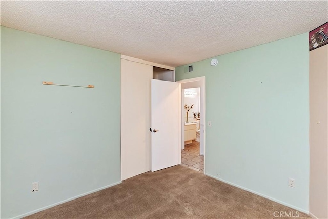 unfurnished bedroom with light colored carpet and a textured ceiling