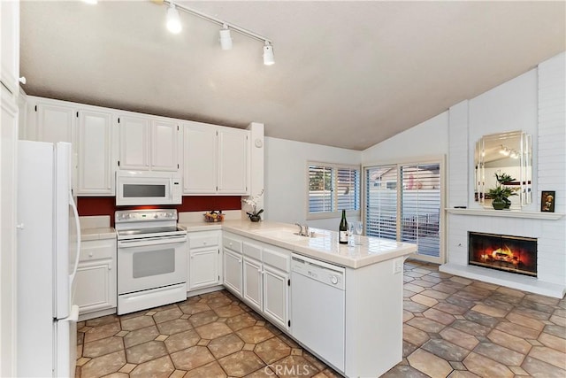 kitchen featuring lofted ceiling, a brick fireplace, kitchen peninsula, white appliances, and white cabinetry