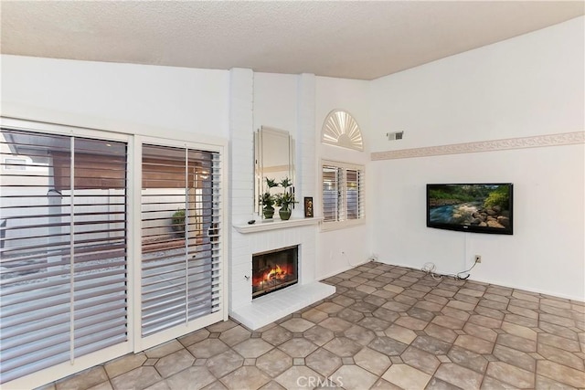 unfurnished living room with a textured ceiling and a brick fireplace