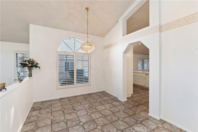 unfurnished dining area with vaulted ceiling, an inviting chandelier, and sink