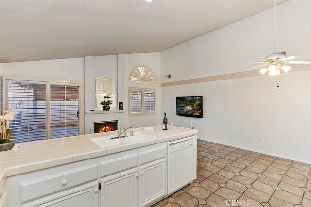 kitchen with white dishwasher, sink, white cabinetry, and tile counters