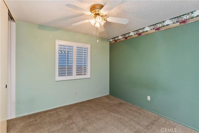 carpeted empty room with ceiling fan and a textured ceiling