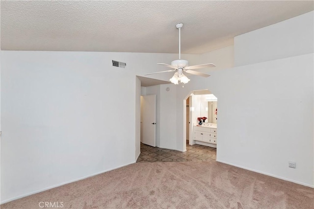 unfurnished room with ceiling fan, vaulted ceiling, and a textured ceiling