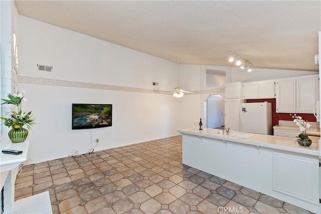 kitchen featuring ceiling fan, vaulted ceiling, sink, white cabinetry, and white refrigerator