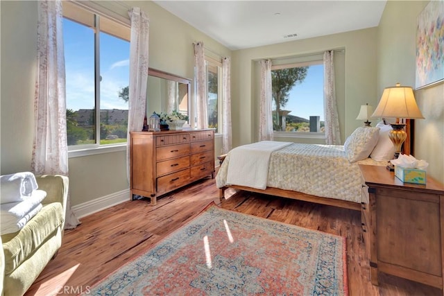 bedroom with multiple windows and light wood-type flooring