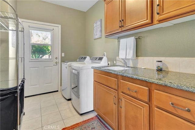 laundry area with cabinets, washing machine and dryer, light tile patterned flooring, and sink