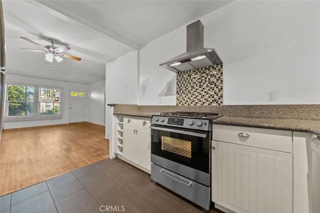 kitchen with backsplash, dark wood-type flooring, white cabinets, wall chimney range hood, and stainless steel stove