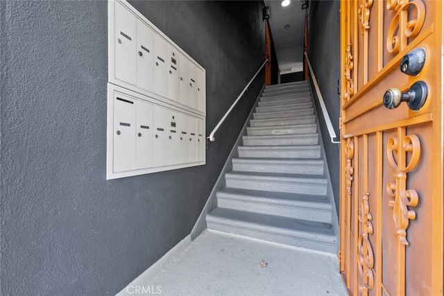 staircase with carpet flooring and a mail area