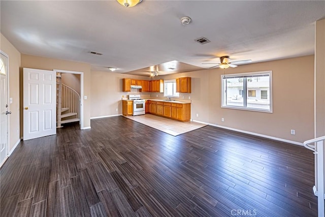 unfurnished living room with ceiling fan, wood-type flooring, and sink