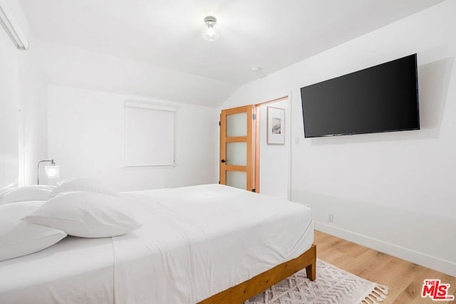 bedroom featuring wood-type flooring and vaulted ceiling