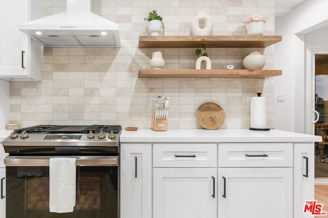 kitchen with gas range, exhaust hood, white cabinets, and decorative backsplash