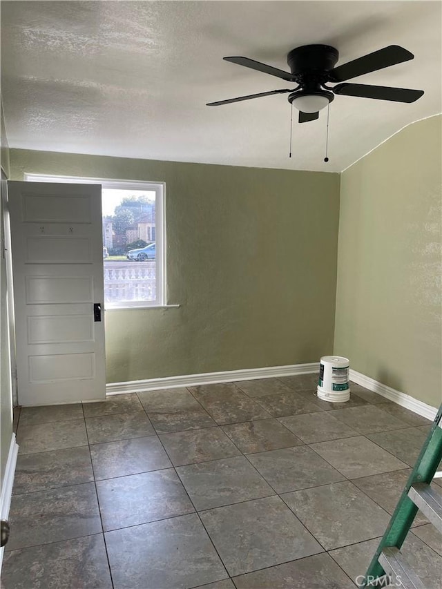 spare room with a textured ceiling, a ceiling fan, and baseboards