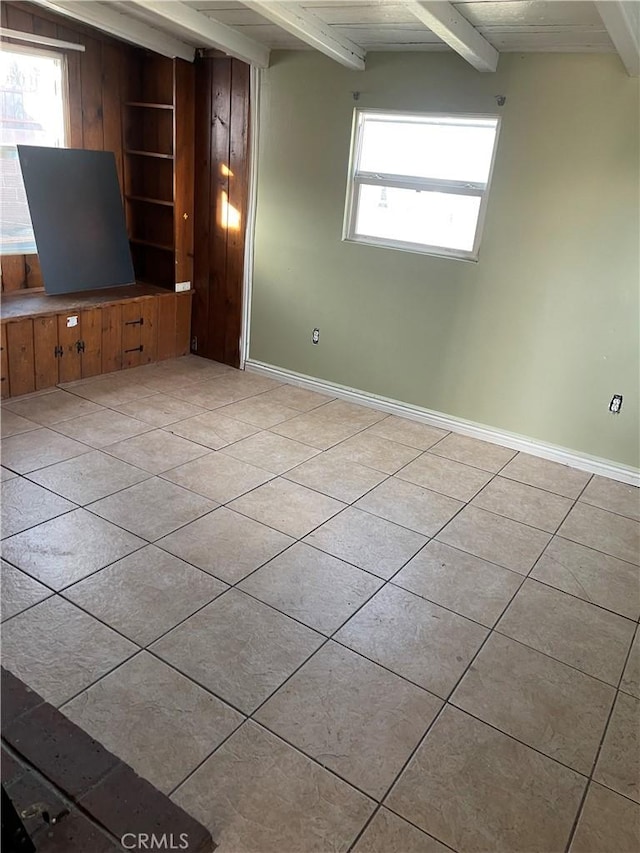 unfurnished living room featuring beam ceiling, light tile patterned floors, baseboards, and built in features