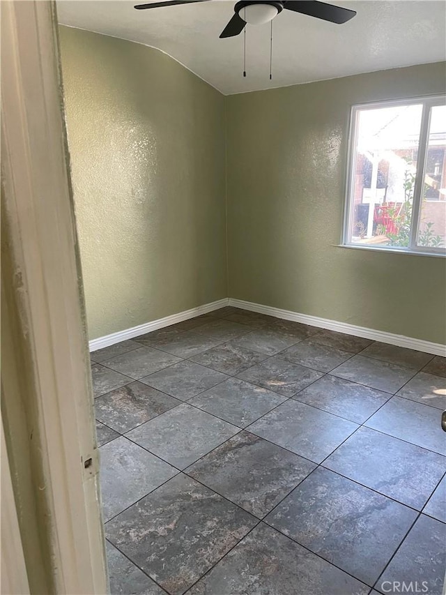 empty room featuring a ceiling fan, baseboards, and a textured wall